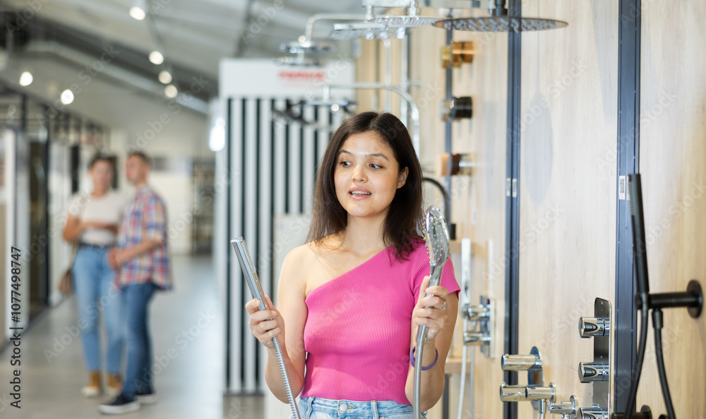 Obraz premium Young girl choosing a shower head in a hardware store
