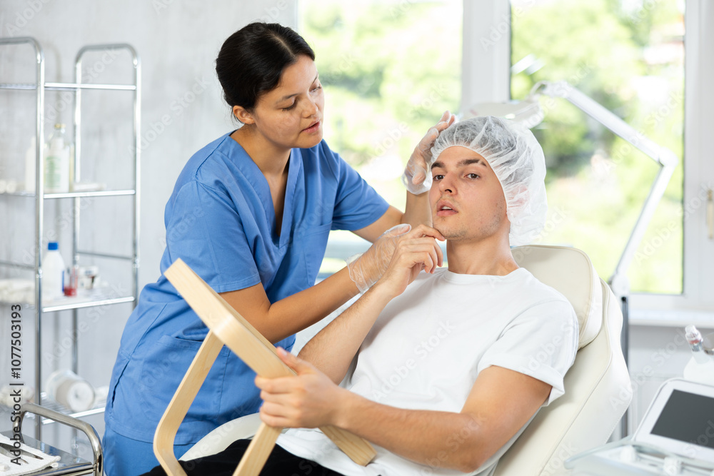 Obraz premium Patient eagerly looked into the mirror as cosmetic doctor displayed results of her work, and his face radiated freshness and glow.