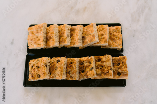 Loaf style focaccia bread served on black trays photo