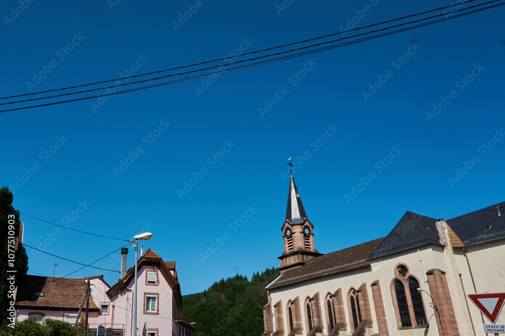 Obraz premium Beautiful clear sky over a traditional village with a church steeple and quaint houses in a rural area
