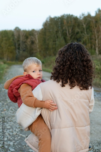 Woman carrying young boy outdoors on a nature trail photo