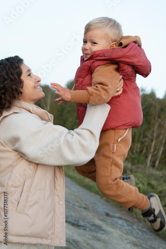 Mother lifting smiling son during outdoor play photo