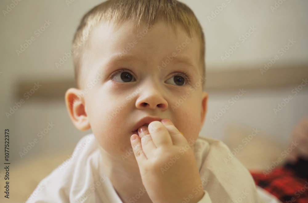 A thoughtful young child lost in contemplation while softly biting his nails A thoughtful young child lost in contemplation while softly biting his nails
