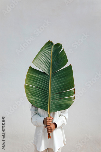 Unrecognizable person carrying palm leaf photo