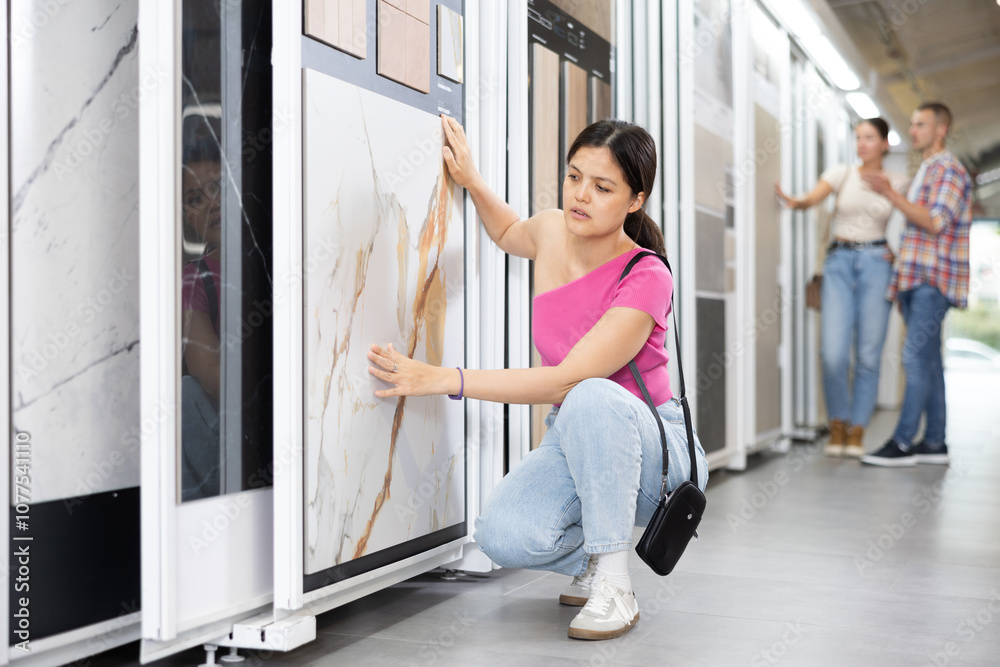 Positive woman wants to buy stone technical tiles for flooring or wall cladding in the materials department of a hardware store Positive woman wants to buy stone technical tiles for flooring or wall cladding in the materials department of a hardware store
