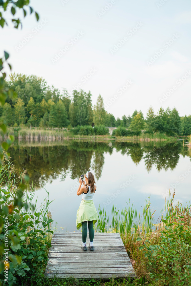 A woman takes pictures of a lake A woman takes pictures of a lake