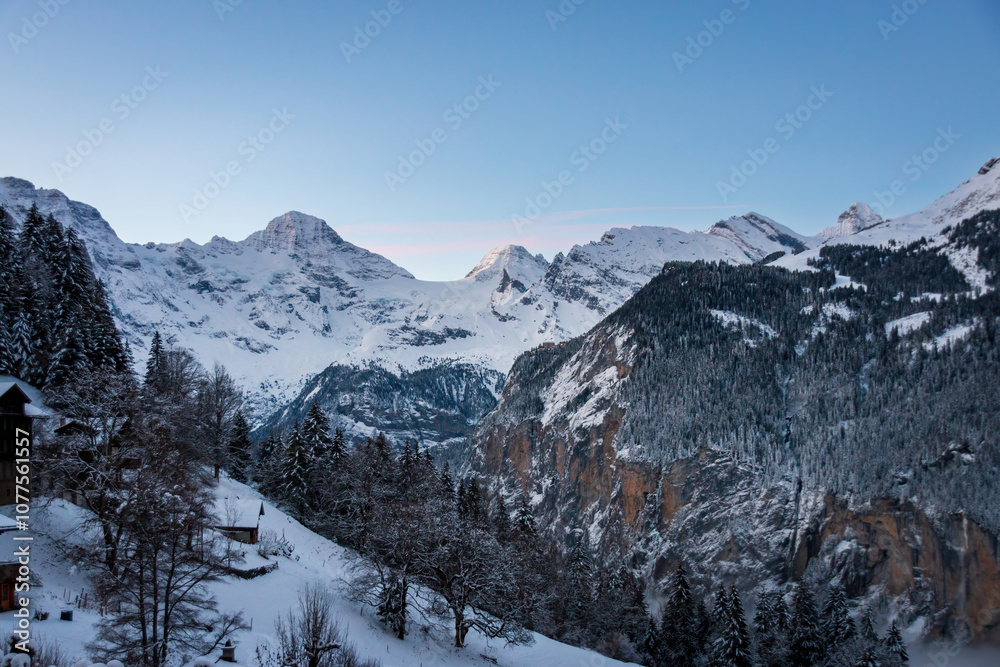 Scenic view of Lauterbrunnen Valley, Switzerland seen from Wengen with snowcovered mountains with Breithorn (left) and Tschingelhorn (right) in winter against blue sky at sunset