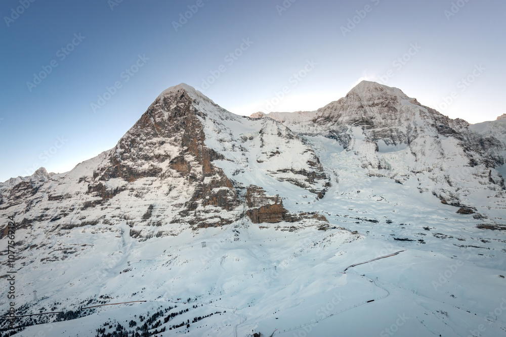 Scenic view of snowcovered Eiger and Mönch mountains in Switzerland early in the morning against blue sky