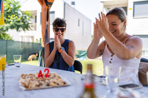 Two women celebrating birthday with cake at outdoor party photo