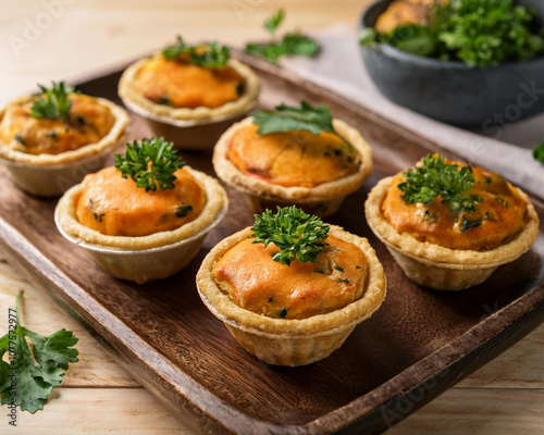 Mini vegan pies with sweet potato and spinach, garnished with fresh herbs, on a rustic wooden board,AI.