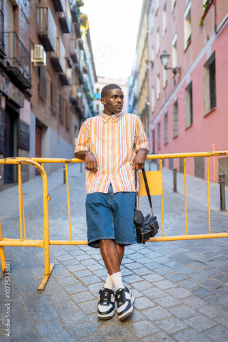 Portrait of black man leaning on a barricade in a colorful city street photo