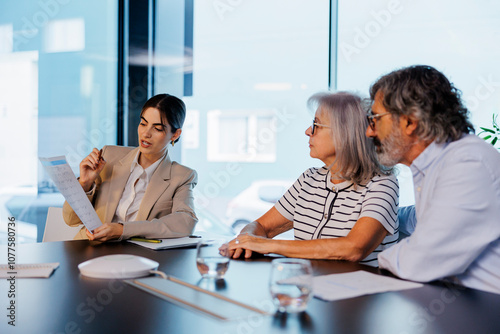 Financial advisor explaining documents to senior couple in meeting photo