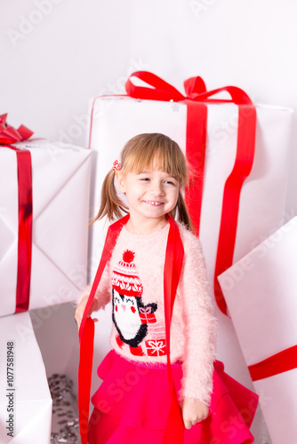 Joyful Girl Playing with Wrapped Holiday Gifts and Red Ribbons