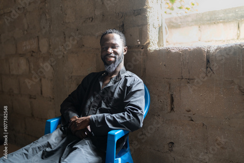 Senegalese man smiling sitting on chair in concrete room photo