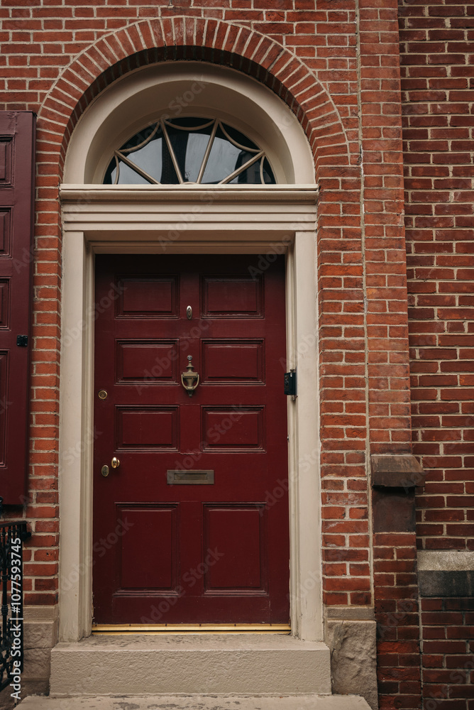 Red door with a semi-circular window on a brick townhouse.
Red door with a semi-circular window on a brick townhouse.