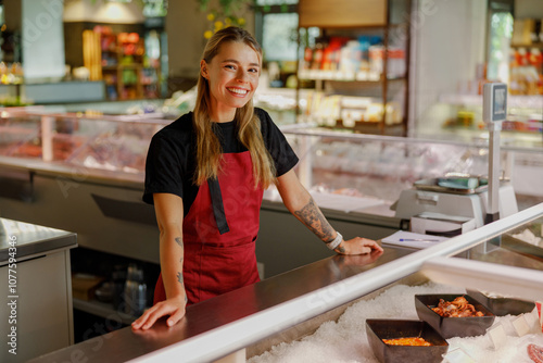 Canvas Print A cheerful fishmonger proudly stands at a seafood counter, showcasing a variety
