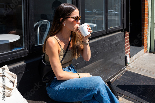 Tourist sitting on a bench sips a takeaway coffee in new York photo