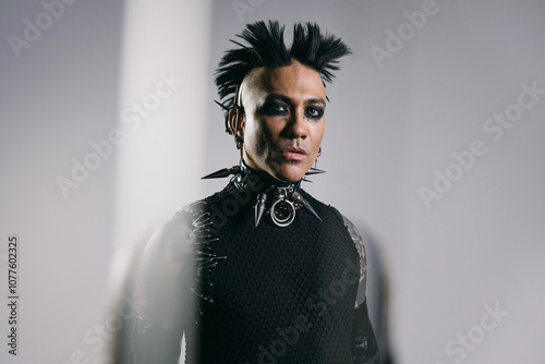 Man with bold punk mohawk and spiked accessories in dramatic lighting photo