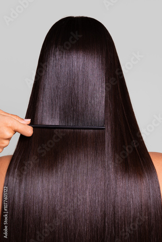 Woman having her long, straight, dark hair combed with a black comb