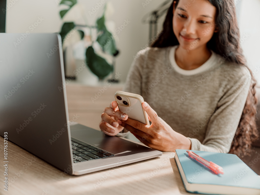 Smiling Woman Using Smartphone and Laptop in Cozy Home Office Smiling Woman Using Smartphone and Laptop in Cozy Home Office