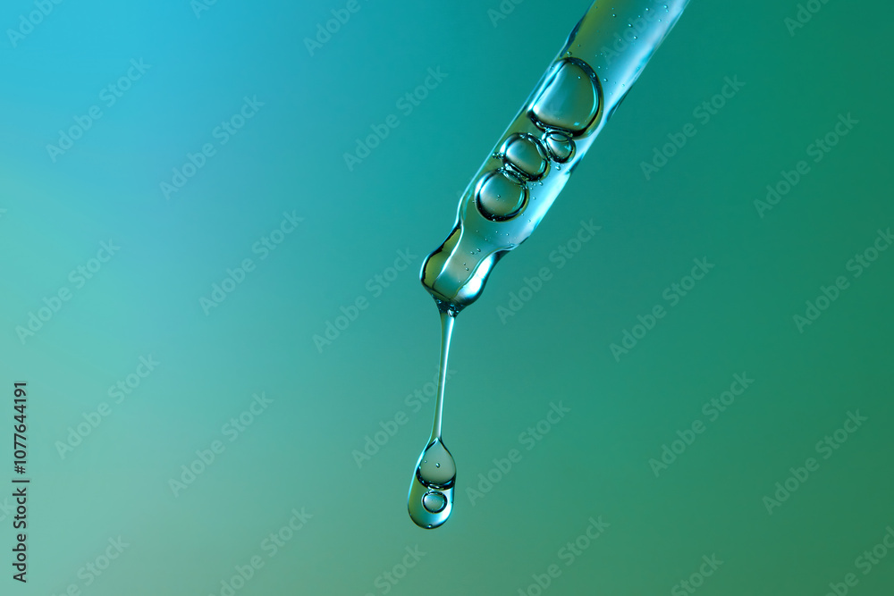 Clear glass pipette with a drop of cosmetic product falling down. Clear glass pipette with a drop of cosmetic product falling down.