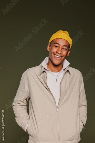 Man wearing beanie smiling with hands in pockets in studio photo