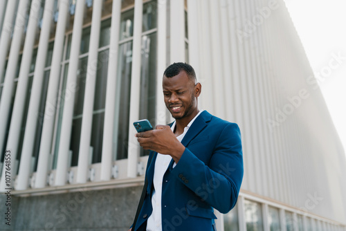 Businessman checking phone in front of modern building photo