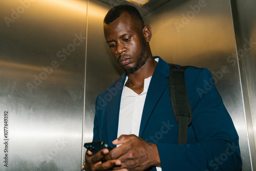 Businessman using smartphone in elevator photo