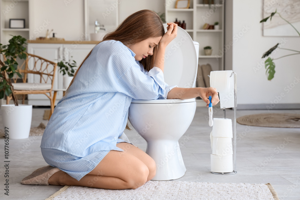 Upset young woman with pregnancy test sitting near toilet bowl in restroom Upset young woman with pregnancy test sitting near toilet bowl in restroom