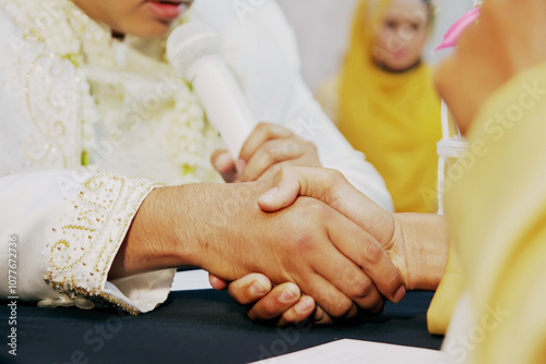 muslim wedding ceremony. The groom's hand shook hands with the bride's parent. It's called Ijab Kabul photo