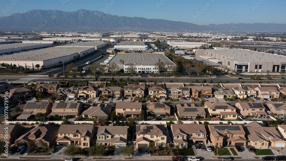 Jurupa Valley, California, USA - November 9, 2024: Afternoon sun shines on newly constructed industrial warehouses and suburban homes.