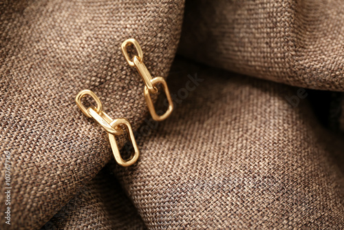 Beautiful golden earrings on fabric background, closeup photo