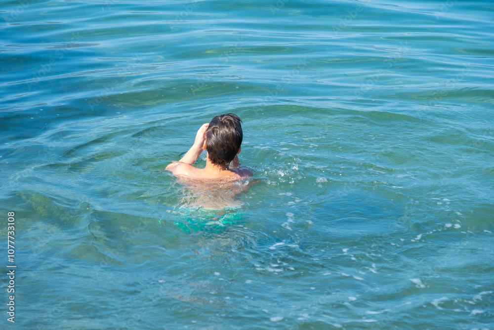 child swims in in open water, sea, confronting fear deep water and potential dangers drowning, enjoying active summer holidays, Water activities, childhood adventure child swims in in open water, sea, confronting fear deep water and potential dangers drowning, enjoying active summer holidays, Water activities, childhood adventure