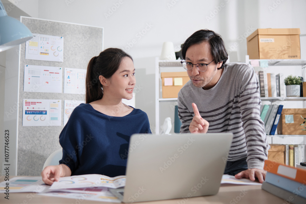 Two young Asian startup company partners discuss and brainstorm in casual small business office, marketing planning jobs on a laptop, and freelance work as E-commerce entrepreneur and coworker team. Two young Asian startup company partners discuss and brainstorm in casual small business office, marketing planning jobs on a laptop, and freelance work as E-commerce entrepreneur and coworker team.