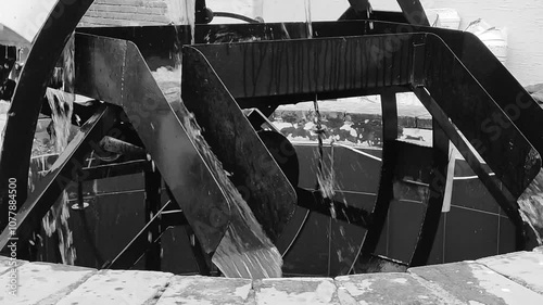 Water wheel of metal on a well dispensing water black and white color 