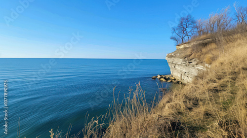 A serene sky view from the edge of a cliff, the ocean meeting the horizon under a clear blue sky photo