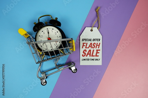 Flash Sale text on price tag with trolley shopping cart and alarm clcok top view on purple geometric background photo