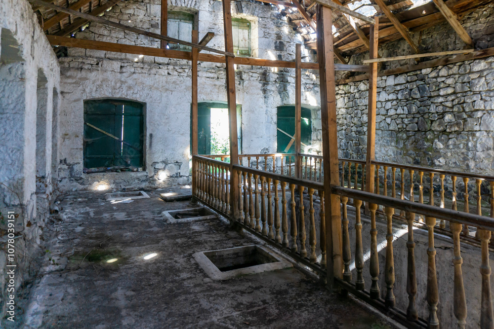 Interior of an old abandoned winery. Stone walls, wooden railings and stairs and windows, a destroyed roof Interior of an old abandoned winery. Stone walls, wooden railings and stairs and windows, a destroyed roof