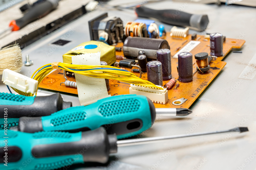 Closeup view of screwdrivers and electronic circuit board with components of microchip, integrated circuits, capacitors, resistances and electronic connections Closeup view of screwdrivers and electronic circuit board with components of microchip, integrated circuits, capacitors, resistances and electronic connections