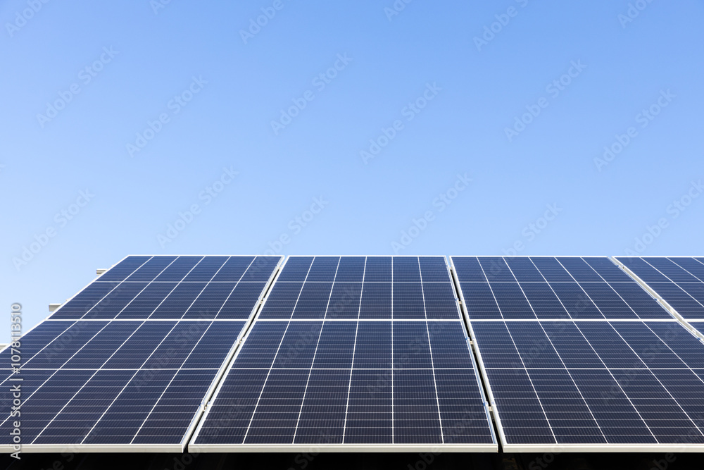 Aerial view of solar panel cells on clear blue sky background. Alternative energy concept. Modern house with solar panels stand-alone photovoltaic plant system on household metal sheet roof Aerial view of solar panel cells on clear blue sky background. Alternative energy concept. Modern house with solar panels stand-alone photovoltaic plant system on household metal sheet roof