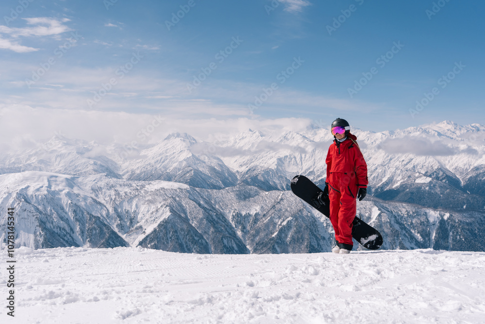 happy woman snowboarder wearing mask on the slope on sunny winter day, stunning mountain landscape on background