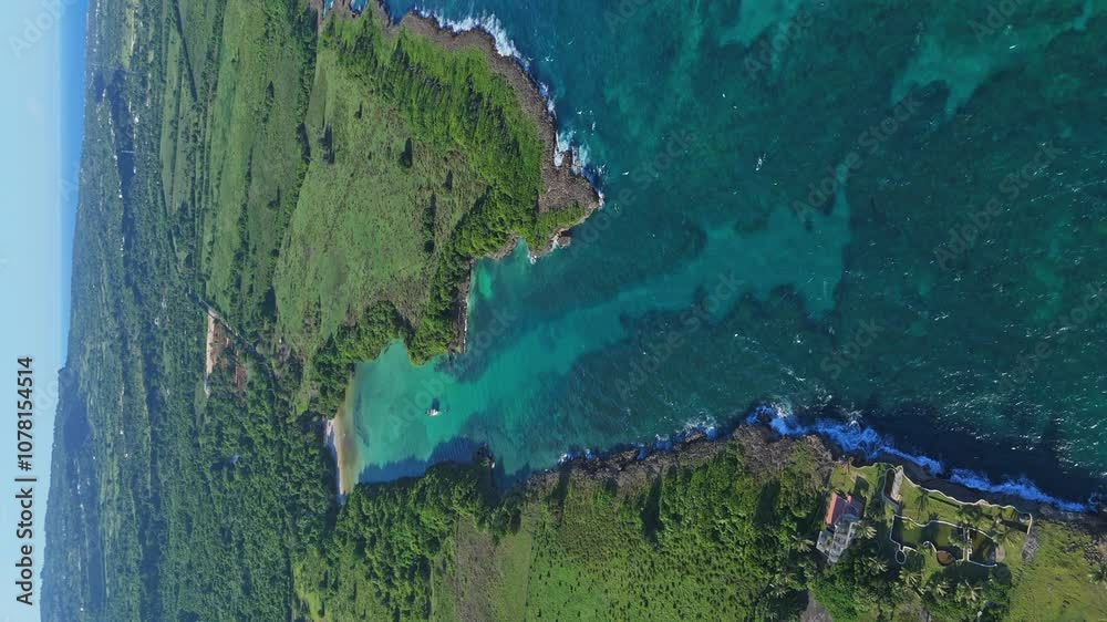 Vertical aerial pan right over Playa Diamante’s turquoise bay and rugged coastline, Dominican Republic. Bird's eye view, panoramic scenery