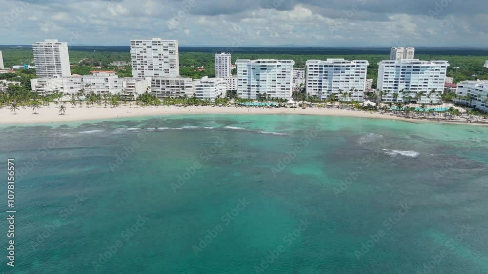 Aerial view of beachfront resorts along Playa Juan Dolio, Dominican Republic. Pan right reveals beautiful turquoise water of the Caribbean Sea Aerial view of beachfront resorts along Playa Juan Dolio, Dominican Republic. Pan right reveals beautiful turquoise water of the Caribbean Sea