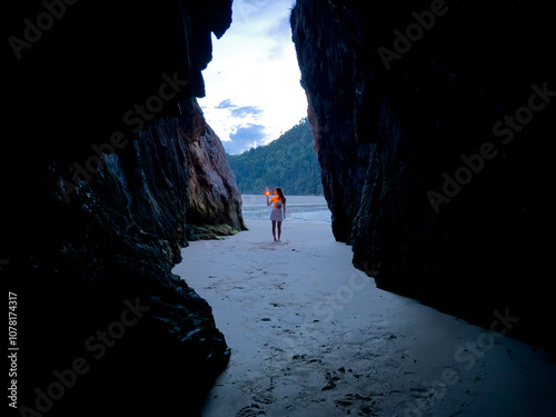 young woman lights lighter in a cave on the beach photo