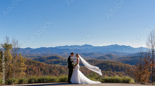 A bride and groom stand together on a mountaintop overlooking a stunning view of the Smoky Mountains. The wind blows through the bride's veil, adding a touch of magic to the moment