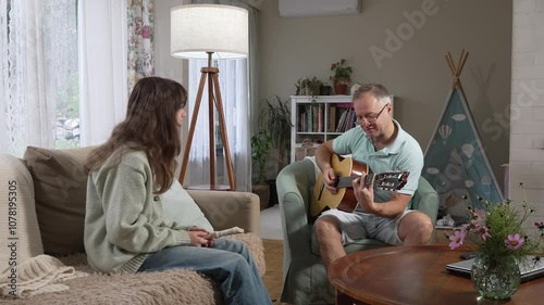 A middle-aged man and a 12-year-old girl enjoying a musical moment together, with him playing guitar and her playing a recorder flute in a cozy setting