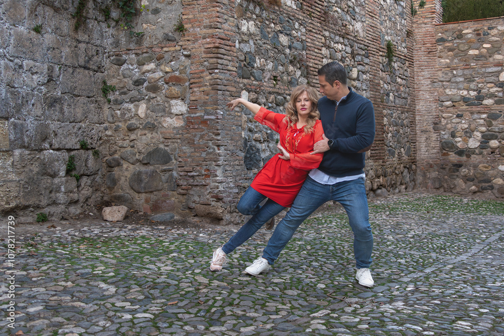 Couple dancing together on cobblestone street with rustic stone wall Couple dancing together on cobblestone street with rustic stone wall