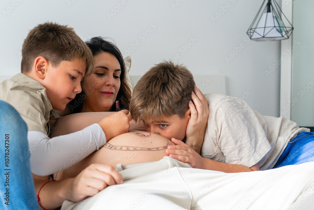 Pregnant mother with her two children, one giving her a kiss on the belly and the other painting the belly Pregnant mother with her two children, one giving her a kiss on the belly and the other painting the belly