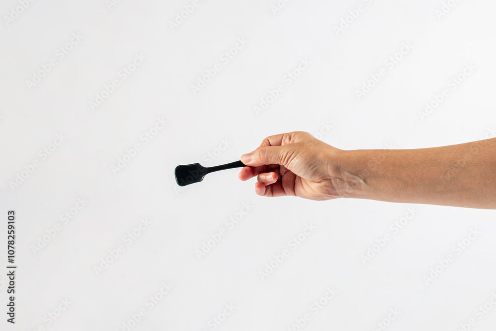 Black ice cream spoon in hand on white background Black ice cream spoon in hand on white background