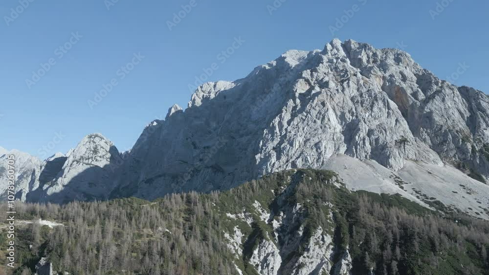 Drone view of Mangart Mountains, Slovenia: jagged peaks, rugged cliffs, lush green valleys, winding alpine roads, dramatic landscape, clear skies, Julian Alps, untouched natural beauty Drone view of Mangart Mountains, Slovenia: jagged peaks, rugged cliffs, lush green valleys, winding alpine roads, dramatic landscape, clear skies, Julian Alps, untouched natural beauty